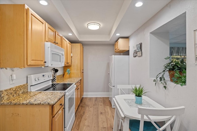 kitchen featuring a raised ceiling, light brown cabinetry, white appliances, and light wood-type flooring