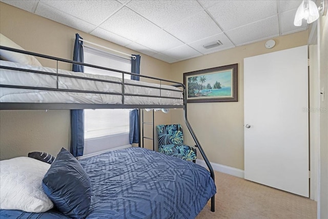 carpeted bedroom with multiple windows and a drop ceiling