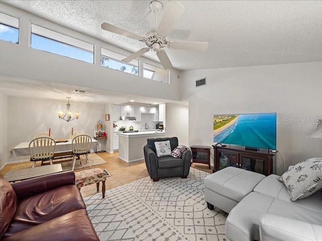 tiled living room featuring a textured ceiling, a towering ceiling, and ceiling fan with notable chandelier