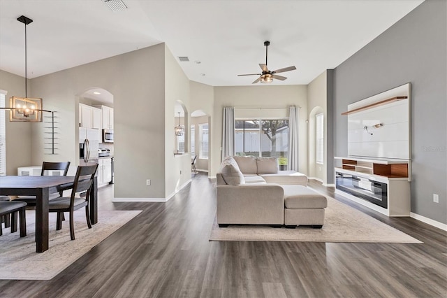 living room with ceiling fan with notable chandelier and dark wood-type flooring