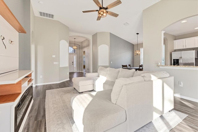 living room with ceiling fan with notable chandelier and dark hardwood / wood-style flooring