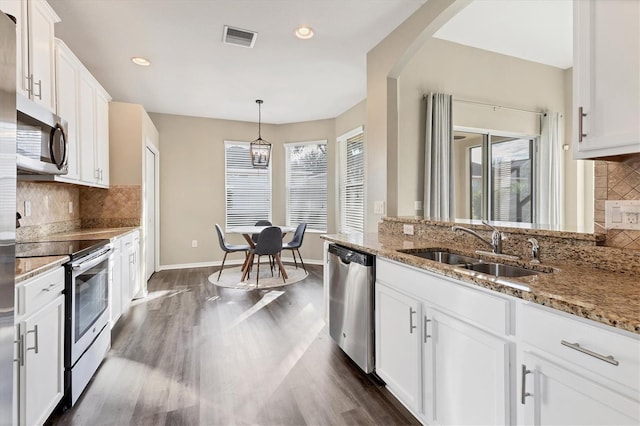 kitchen featuring white cabinetry, sink, hanging light fixtures, decorative backsplash, and appliances with stainless steel finishes