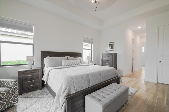 bedroom with a tray ceiling and light hardwood / wood-style flooring