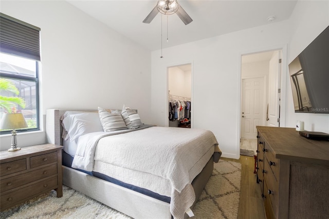 bedroom with a spacious closet, ceiling fan, a closet, and light hardwood / wood-style floors