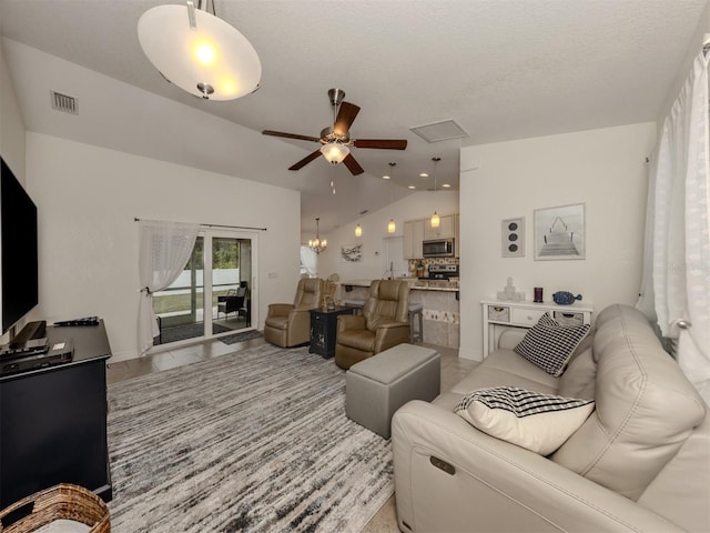 living room featuring ceiling fan with notable chandelier, a textured ceiling, and lofted ceiling