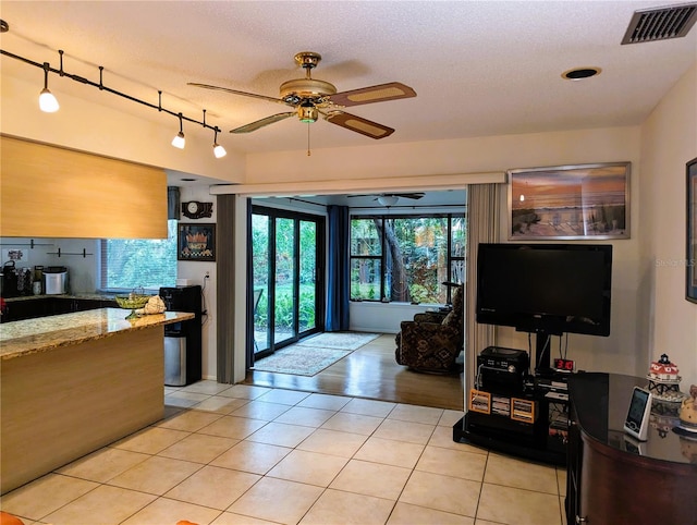 interior space featuring ceiling fan, light tile patterned floors, and a textured ceiling