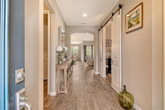 hallway with a barn door and hardwood / wood-style floors