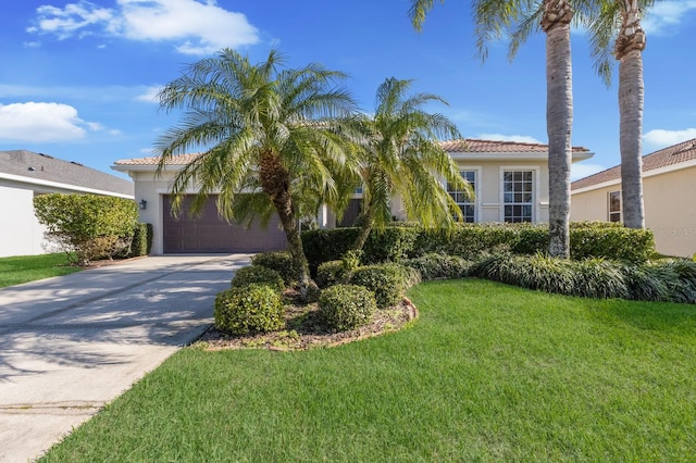 view of front of property featuring a tile roof, stucco siding, concrete driveway, an attached garage, and a front lawn