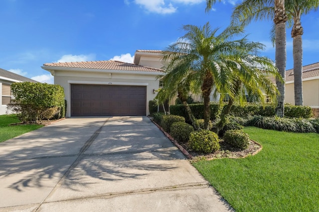 view of front of house featuring driveway, a tiled roof, an attached garage, a front lawn, and stucco siding