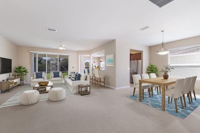 living room featuring light colored carpet, visible vents, ceiling fan, and baseboards