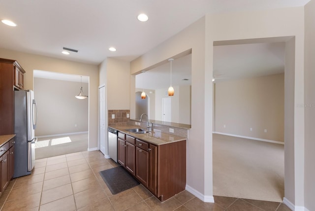 kitchen with light tile patterned floors, tasteful backsplash, light colored carpet, appliances with stainless steel finishes, and a sink