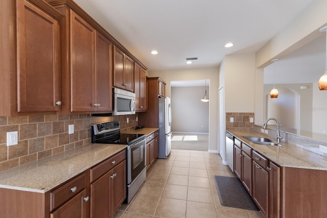 kitchen with light tile patterned floors, light stone counters, stainless steel appliances, and a sink