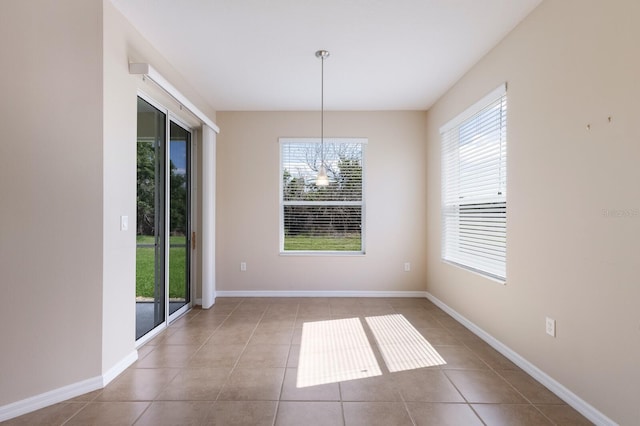 unfurnished dining area with baseboards and tile patterned floors