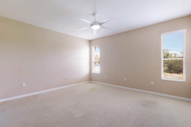 empty room with light carpet, ceiling fan, and baseboards