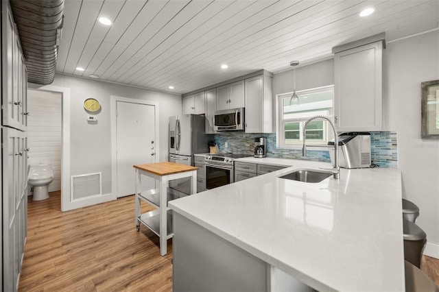 kitchen with pendant lighting, stainless steel appliances, sink, kitchen peninsula, and wooden ceiling