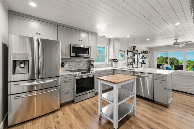 kitchen with kitchen peninsula, appliances with stainless steel finishes, sink, and wooden ceiling