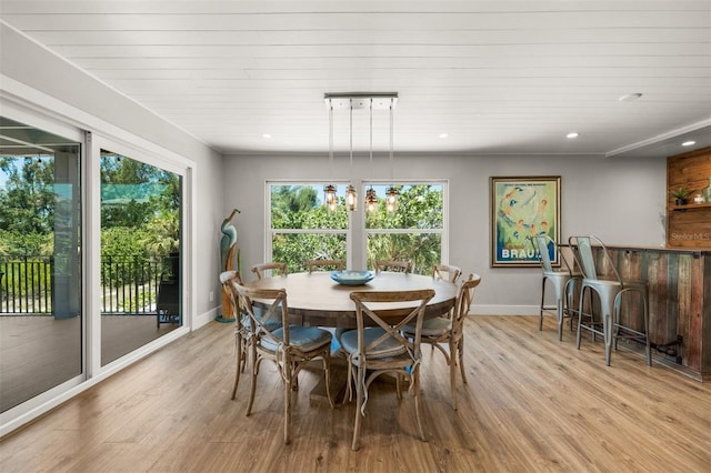 dining room featuring light wood-type flooring, wooden ceiling, and a wealth of natural light