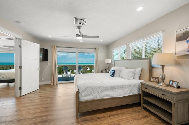 bedroom with ceiling fan, access to exterior, a water view, and light hardwood / wood-style flooring