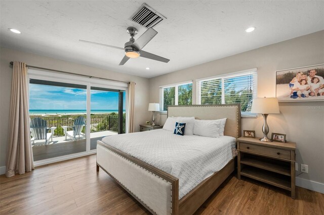 bedroom with ceiling fan, a water view, hardwood / wood-style floors, and access to outside