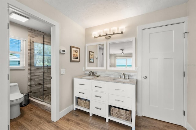 bathroom with toilet, vanity, hardwood / wood-style flooring, a textured ceiling, and an enclosed shower