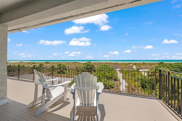 wooden deck with a water view and a beach view