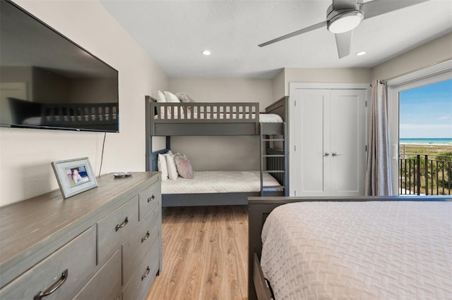 bedroom with ceiling fan, access to outside, light hardwood / wood-style flooring, a water view, and a closet