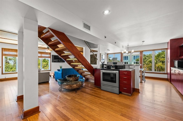 kitchen with hanging light fixtures, a notable chandelier, stainless steel range with electric cooktop, and light hardwood / wood-style floors