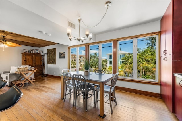 dining room with ceiling fan with notable chandelier and light hardwood / wood-style flooring