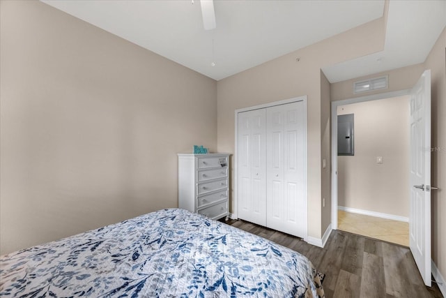 bedroom featuring dark wood-type flooring, ceiling fan, electric panel, and a closet