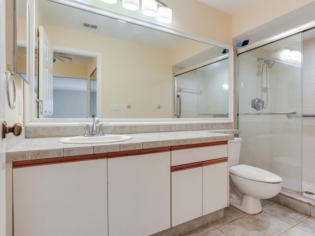 bathroom featuring tile patterned flooring, vanity, toilet, and an enclosed shower