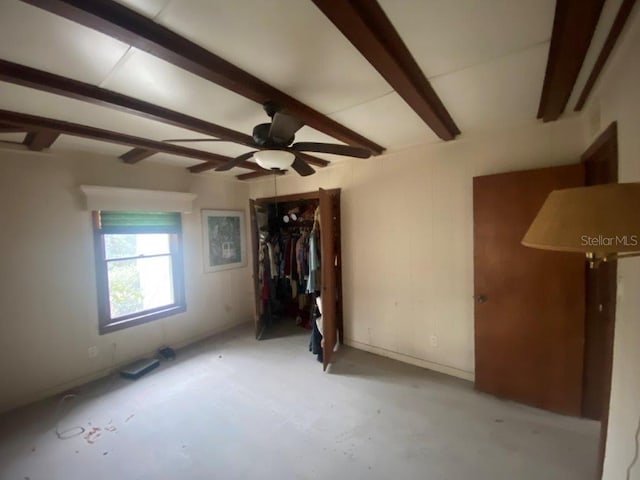 empty room featuring beamed ceiling and ceiling fan