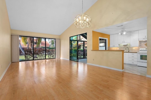 unfurnished living room with light wood-type flooring, ceiling fan with notable chandelier, high vaulted ceiling, and sink