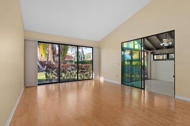 spare room with high vaulted ceiling, wood finished floors, and baseboards