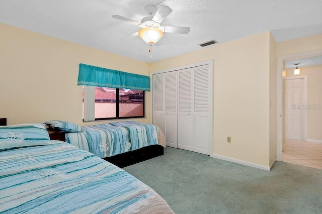 bedroom featuring baseboards, visible vents, a textured ceiling, carpet flooring, and a closet