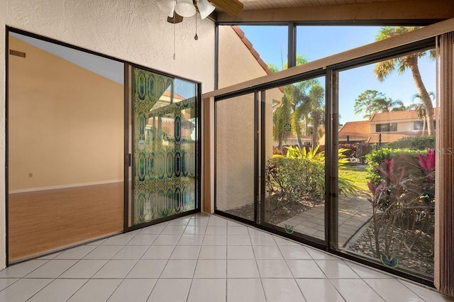 unfurnished sunroom with lofted ceiling with beams, visible vents, and a ceiling fan