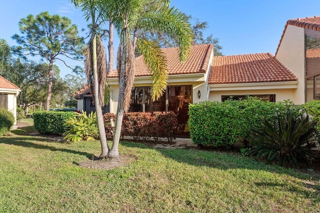 view of front of house with stucco siding, a front yard, and a tiled roof