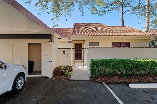 townhome / multi-family property featuring a fenced front yard, a tile roof, a gate, and stucco siding