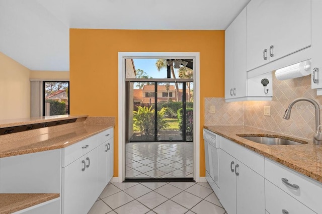 kitchen with light stone counters, a sink, white cabinets, and decorative backsplash