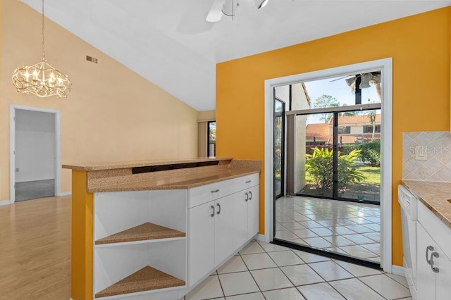 kitchen featuring lofted ceiling, white dishwasher, visible vents, white cabinetry, and tasteful backsplash