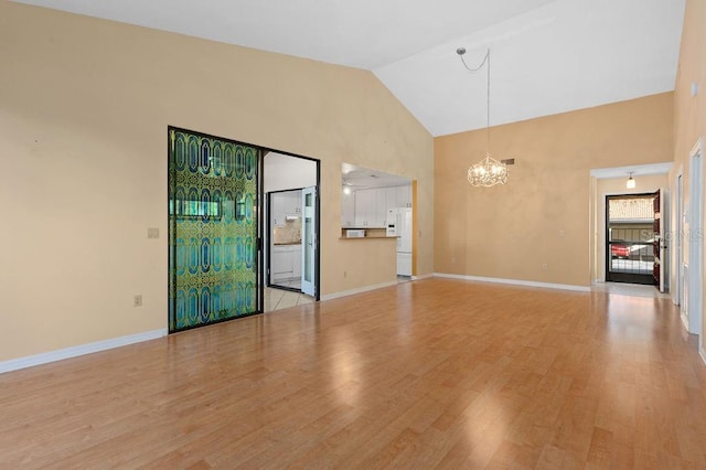 unfurnished living room featuring baseboards, light wood-style flooring, high vaulted ceiling, and a notable chandelier