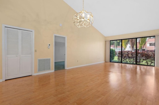 spare room with baseboards, visible vents, light wood-type flooring, high vaulted ceiling, and a notable chandelier