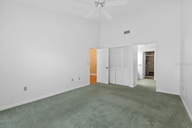 unfurnished bedroom with baseboards, visible vents, a high ceiling, carpet flooring, and a closet