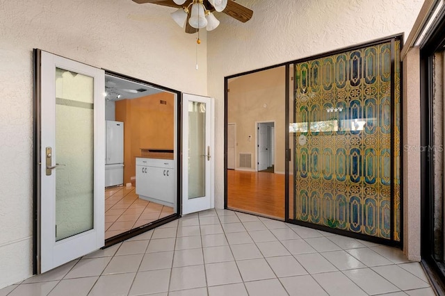 unfurnished bedroom with light tile patterned floors, visible vents, a ceiling fan, a textured wall, and freestanding refrigerator