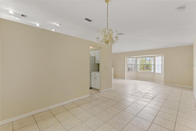 empty room with light tile patterned flooring and an inviting chandelier