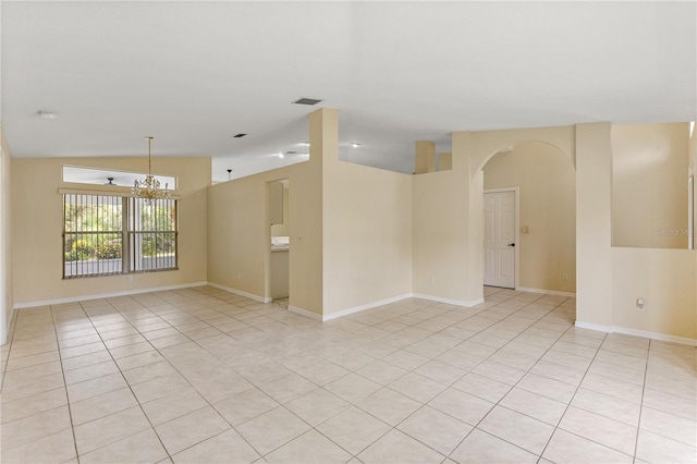 spare room featuring light tile patterned floors, vaulted ceiling, and an inviting chandelier