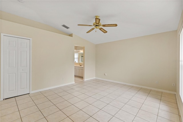 spare room featuring ceiling fan, light tile patterned flooring, and vaulted ceiling