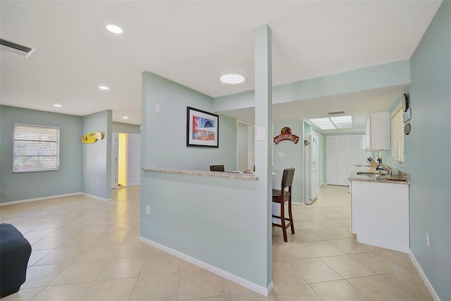 kitchen featuring light tile patterned flooring and white cabinetry