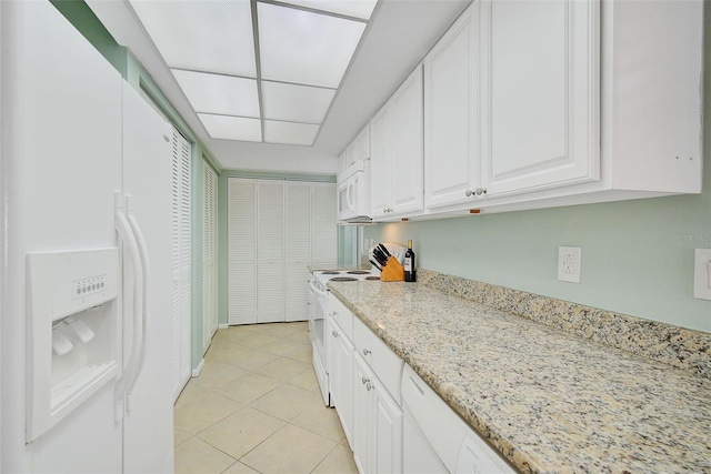 kitchen featuring white cabinetry, light tile patterned floors, light stone countertops, and white appliances