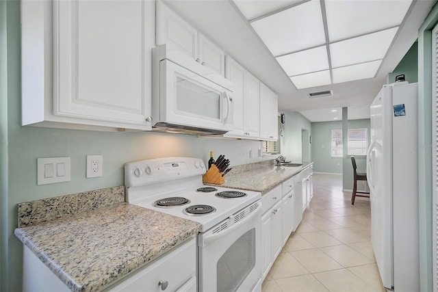 kitchen with light stone countertops, white appliances, sink, light tile patterned floors, and white cabinets