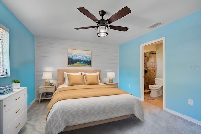 bedroom featuring ceiling fan, light colored carpet, and ensuite bathroom